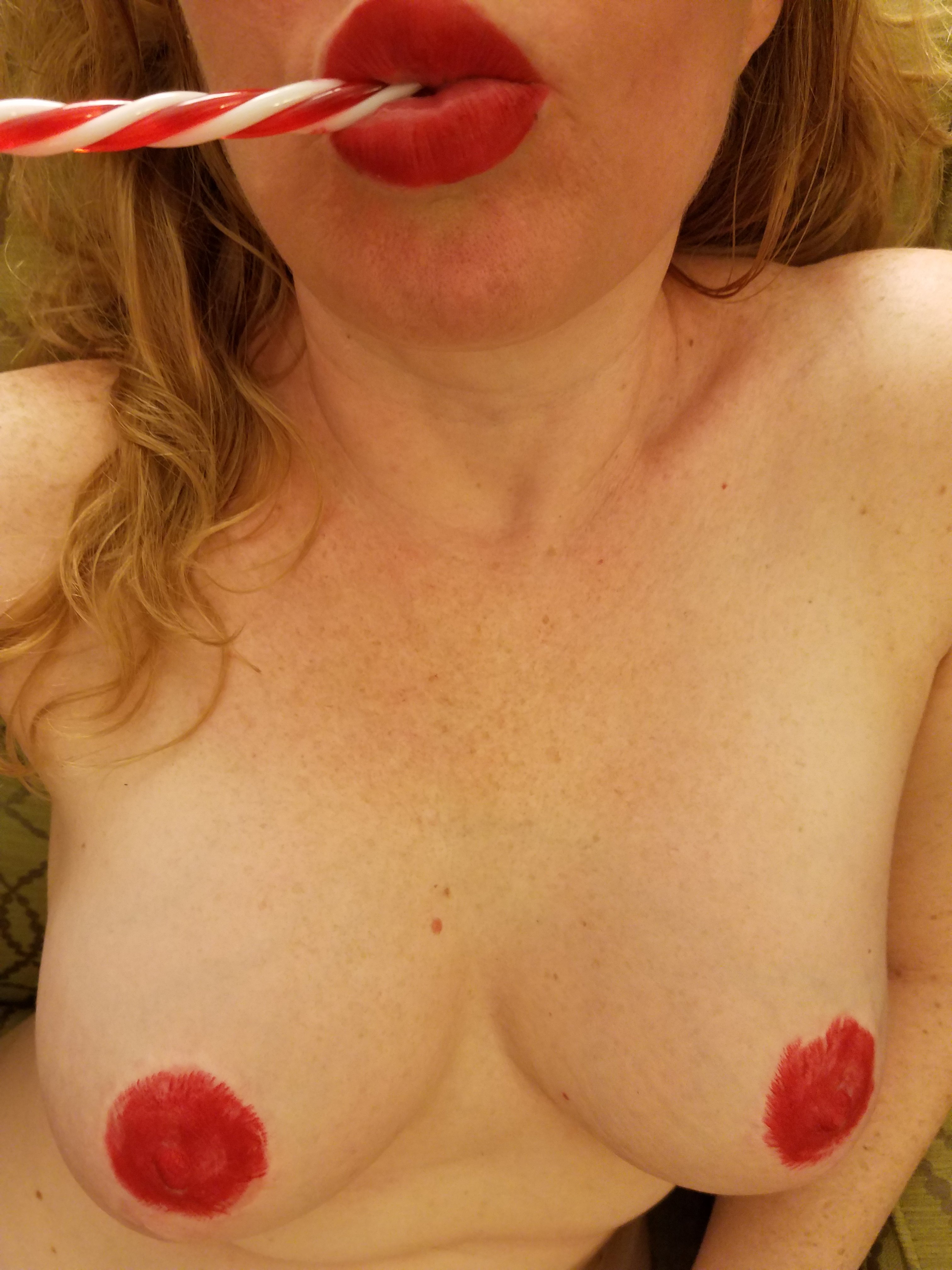 Naked girl with red lips and lipstick nipples suck a candy cane